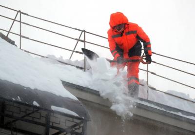 Уборка снега с крыши дома. Фото © ТАСС / Сергей Савостьянов